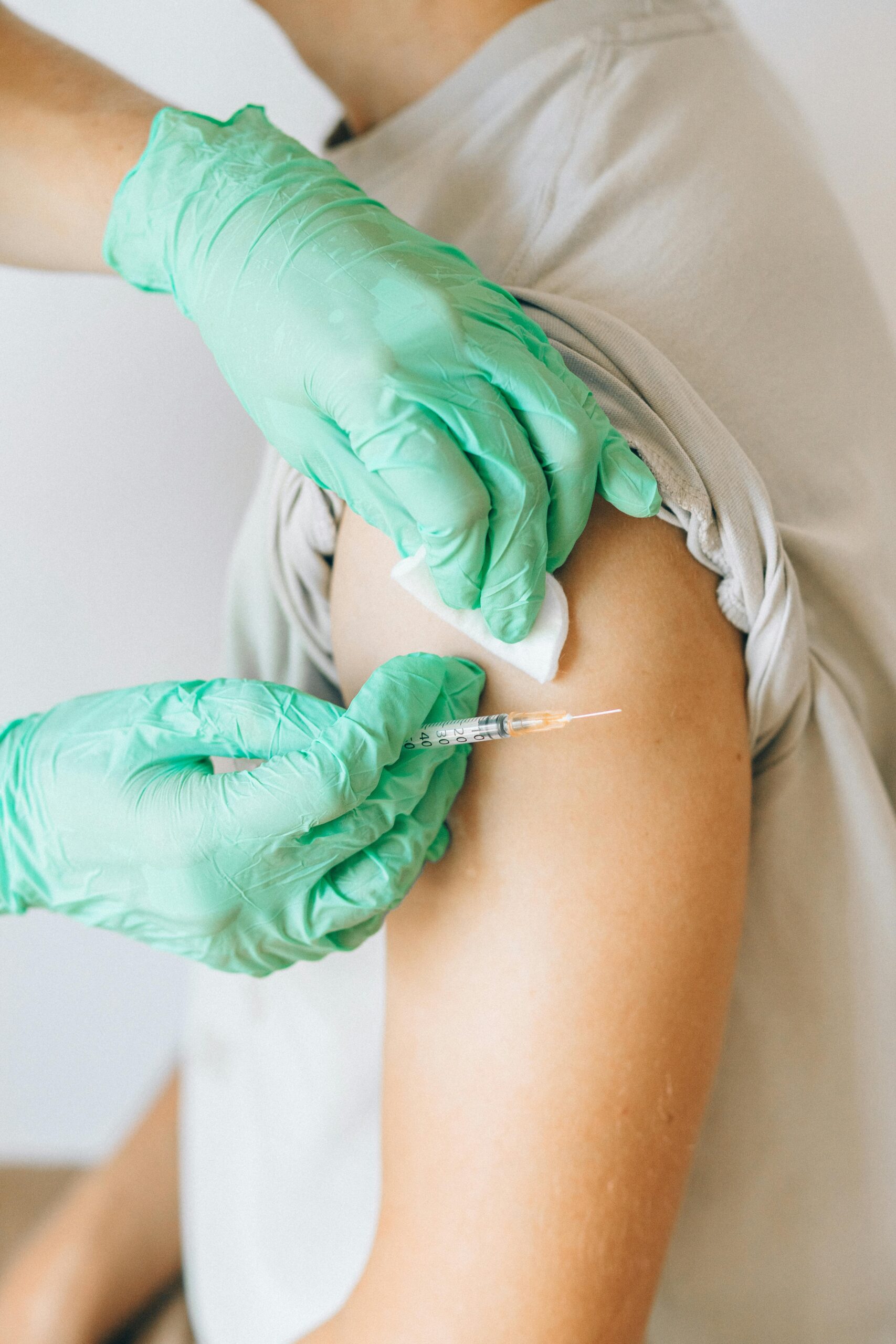 A nurse gives a vaccine injection to a patient's arm with a syringe and cotton.